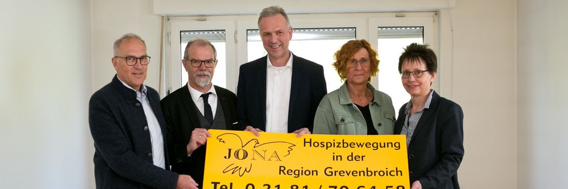 Personengruppe hält Plakat mit Schriftzug "Jona-Hospizbewegung in der Region Grevenbroich und Telefonnummer 02181/706458"