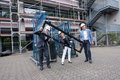 Landrat Hans-Jürgen Petrauschke, Christina Grebe und Johannes Gillrath mit Schutzhelmen halten ein Fenster vor einem Schulgebäude mit Baugerüst.