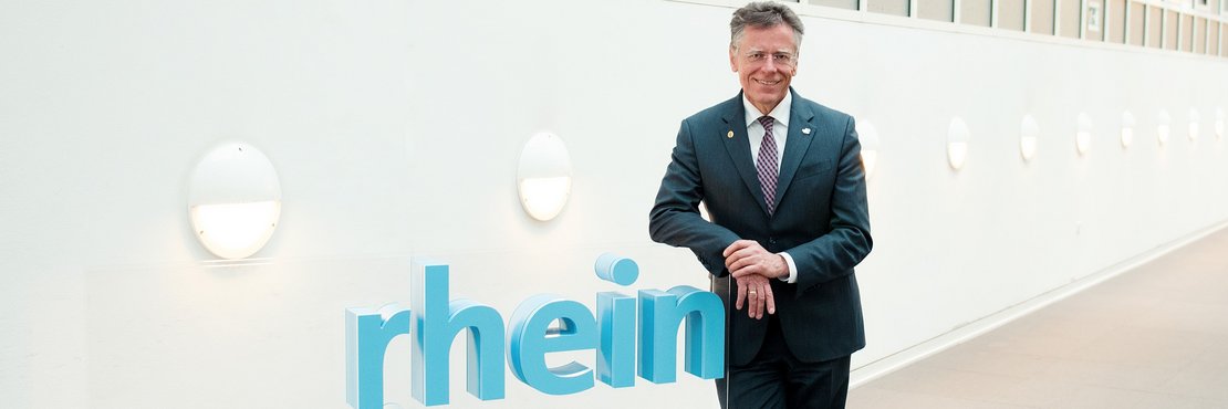 Landrat Hans-Jürgen Petrauschke lehnt an einem 3D-Logo des Rhein-Kreises Neuss