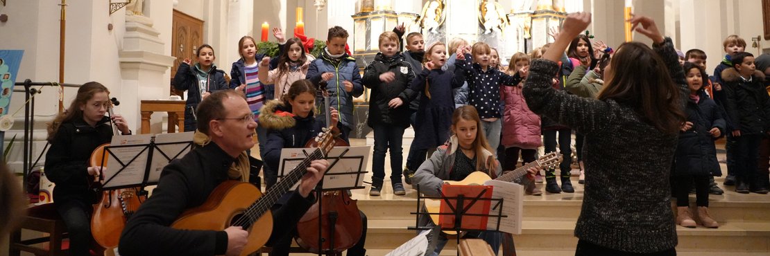 Grundschulkinder und Orchester beim Mitmachkonzert in der Kirche