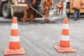 Straßenarbeiter bei der Arbeit. Zwei Pylonen sichern die Straße.