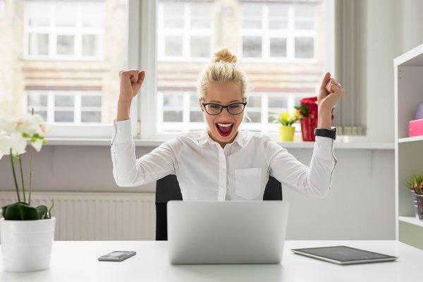 Büro Frau feiert Erfolg vor Laptop